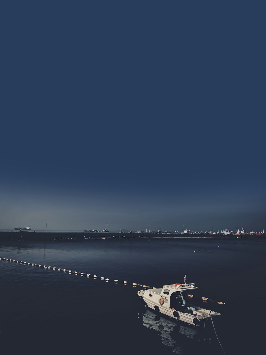 Sea Police patrol boat floating on water near an industrial port.